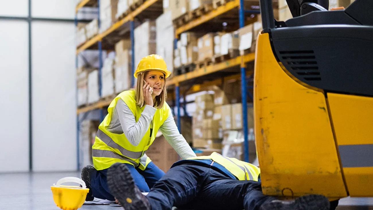 Warehouse supervisor calling an emergency line after the forklift accident