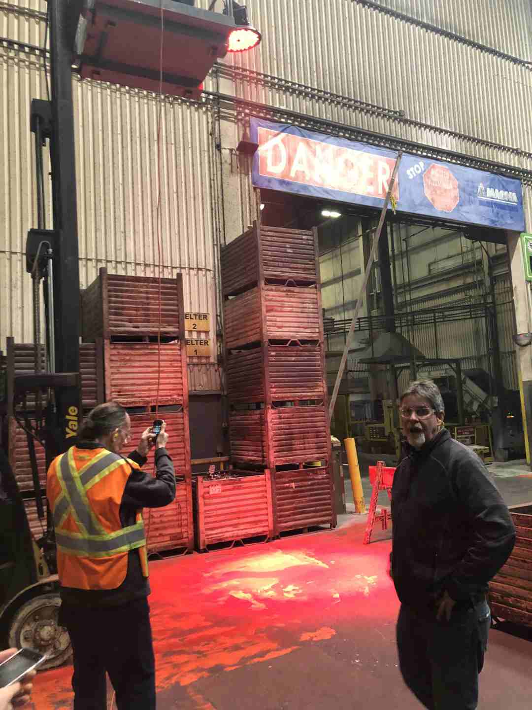 Warehouse workers look at the red light projected onto the warehouse floor