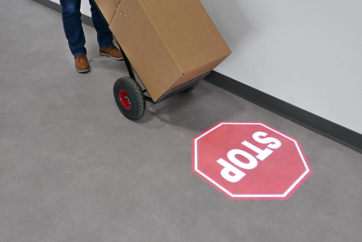 A person carrying the box towards the projected "Stop" Sign
