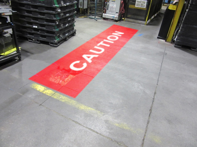 Red "Caution" warning sign projected onto the floor