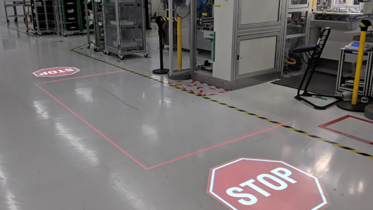 Two stop signs and red lines projected onto the floor to mark a safety zone
